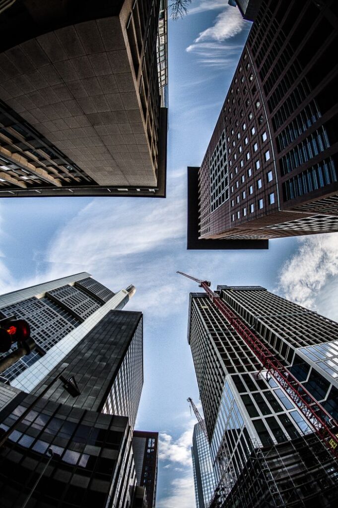 Low-angle view of skyscrapers reaching into a clear blue sky in a bustling urban environment.
